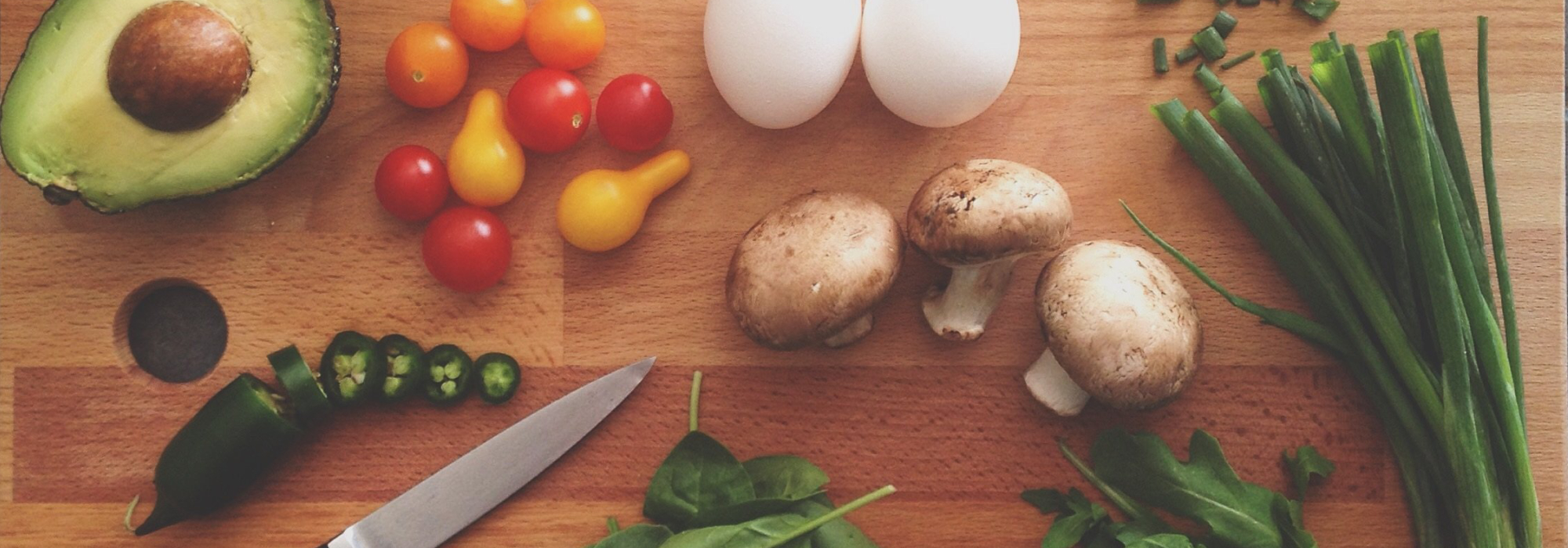 A chopping board with various vegetables in stages of prep